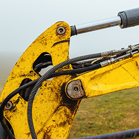 close up of yellow excavator arm hydraulic systems and machinery components for construction site maintenance