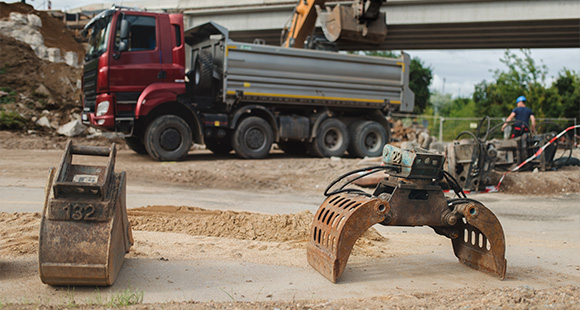 construction site with excavator attachments and dump truck in background heavy machinery operations