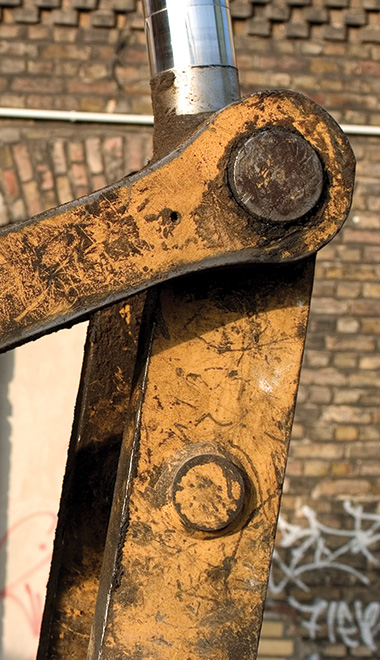 close up of a worn metal hinge on machinery with scratches and dirt clearly visible highlighting industrial strength and durability. heavy equipment part