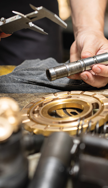 person using calipers to measure metal part on workbench with gears and tools in the background precision mechanical work 1